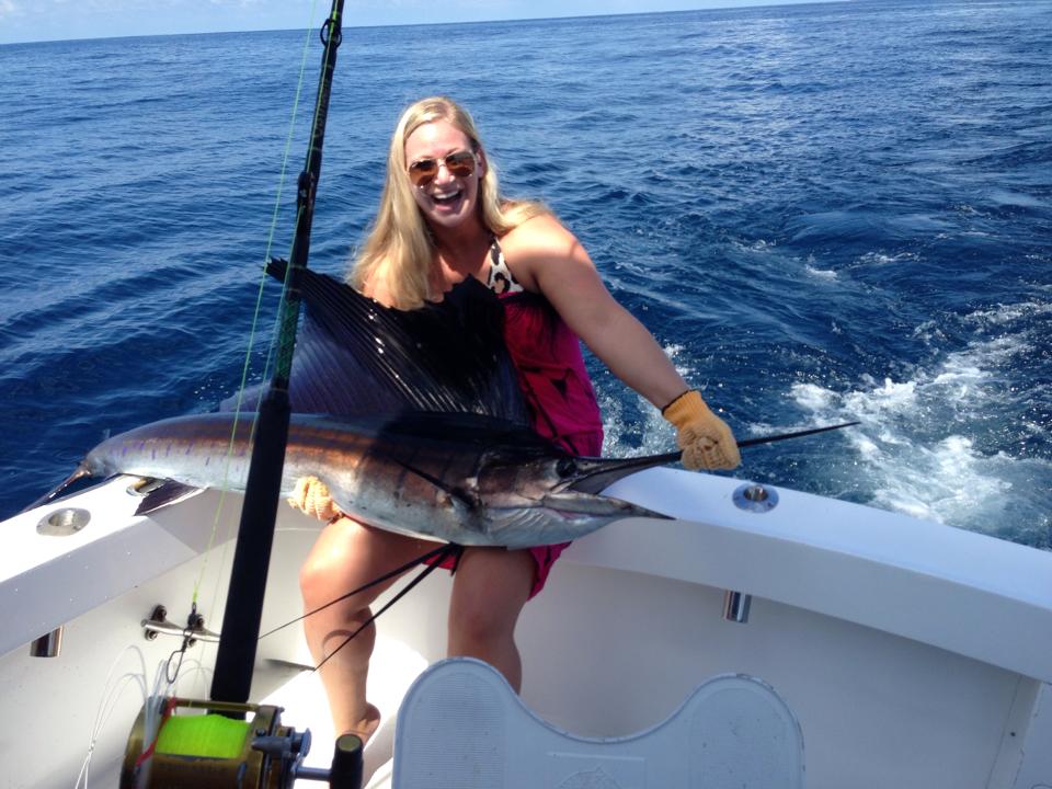 woman smiling with fish she caught on boat